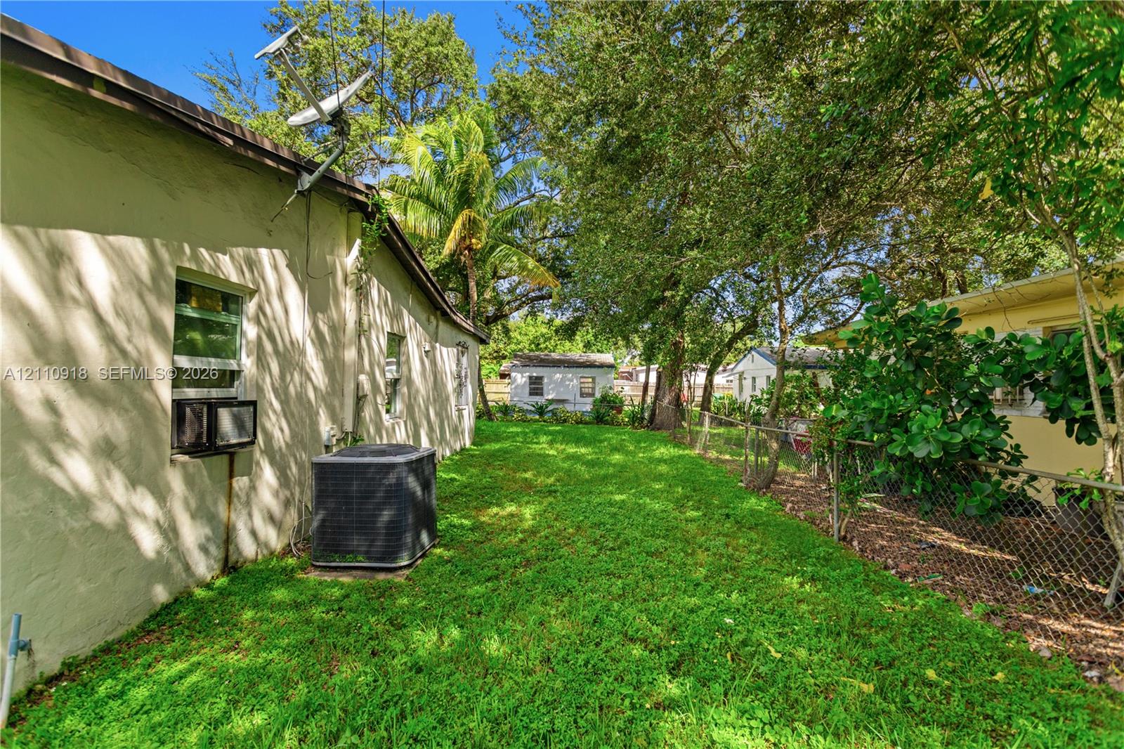 Side yard featuring a grass lawn, chain-link perim