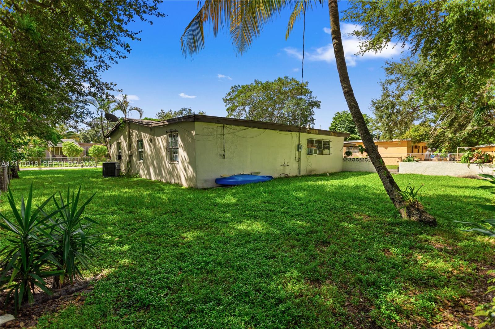 Stucco exterior featuring mature landscaping, palm