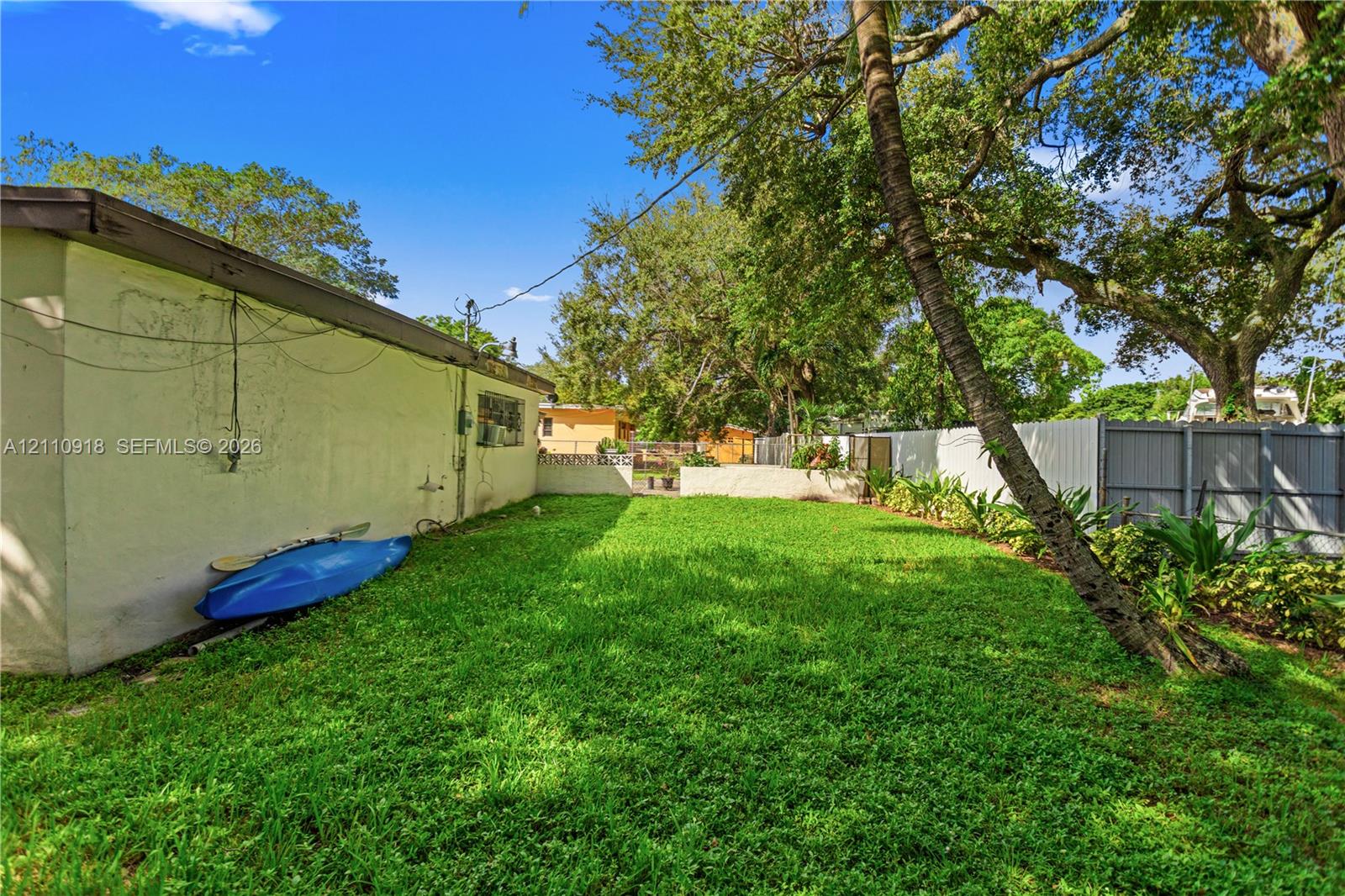 Side yard featuring a grass lawn, mature trees, an