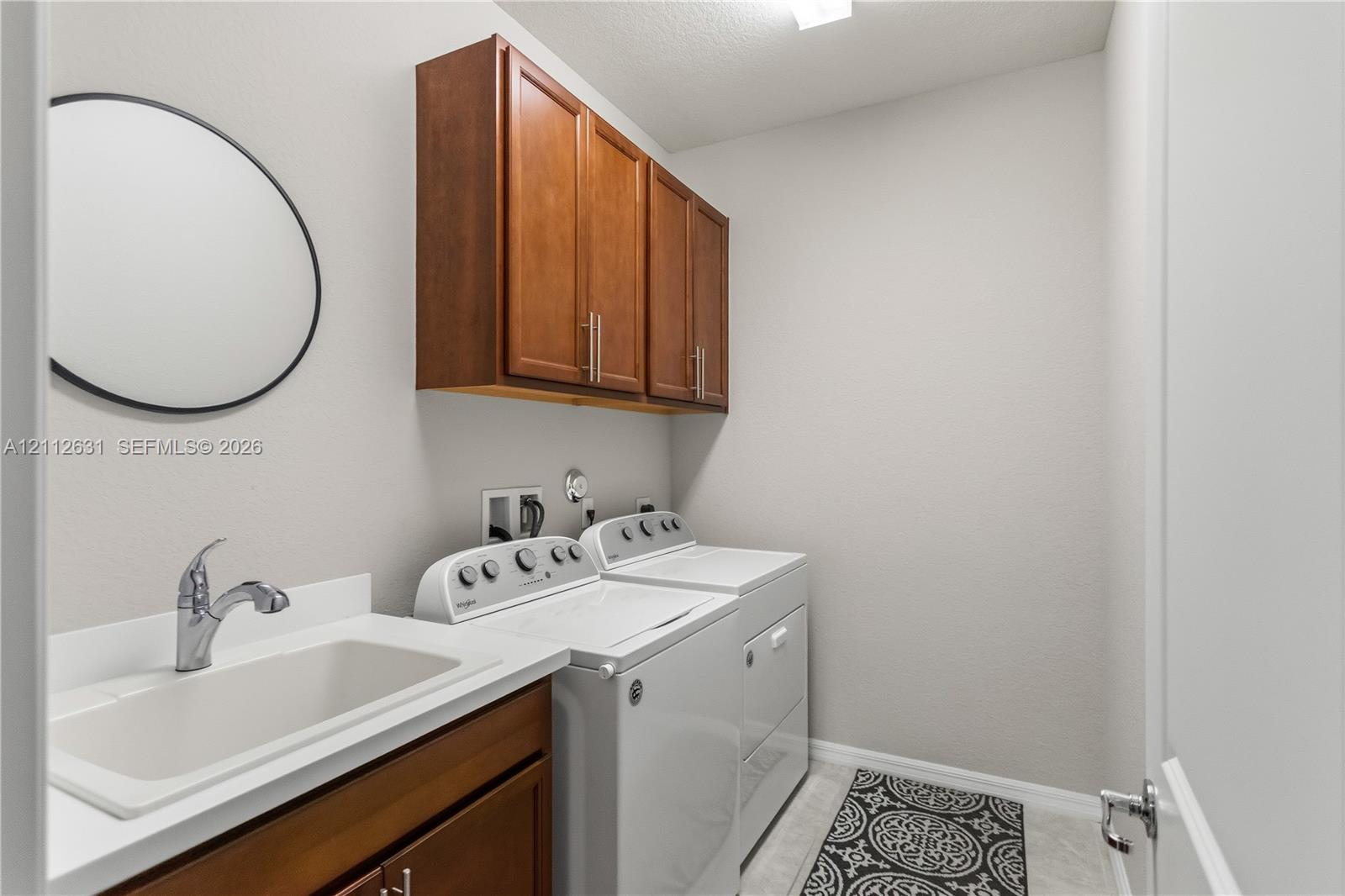 Laundry room featuring wood-finish cabinetry, a ut